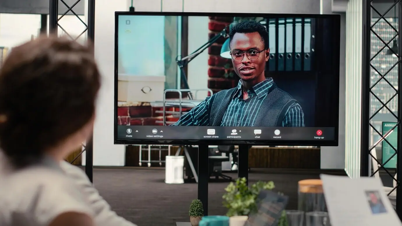 Команда рекрутеров и кандидат-мужчина ведут беседу по видеозвонку, используя веб-камеру и высокотехнологичные инструменты.