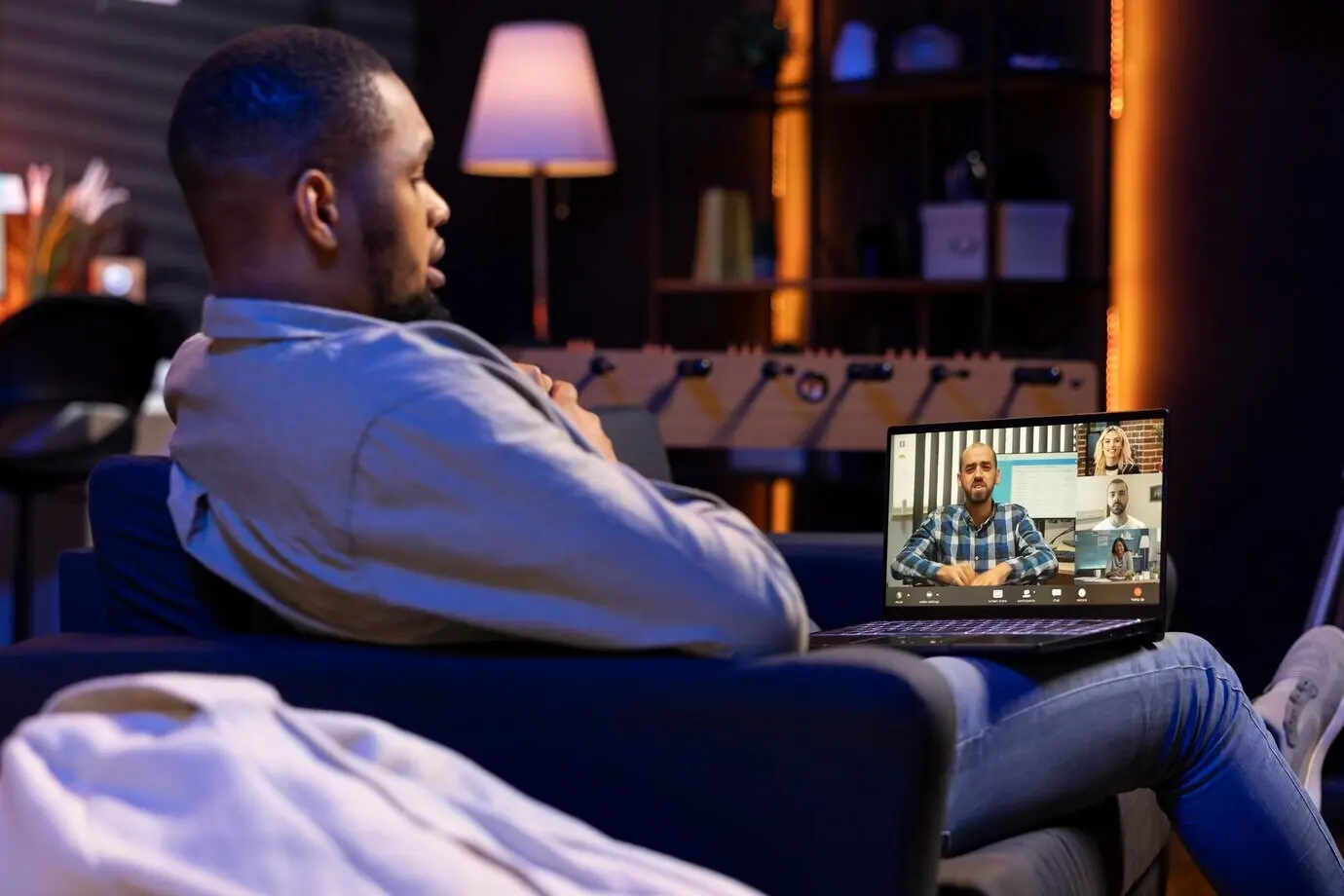 Мужчина, работающий удалённо, машет своим коллегам во время виртуальной встречи.